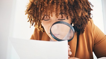 étudiante relisant sa lettre de motivation à la loupe pour éviter les érreurs